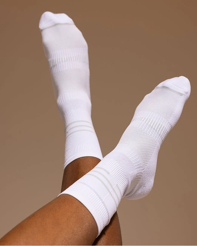 Crossed legs in white crew socks on a tan backdrop
