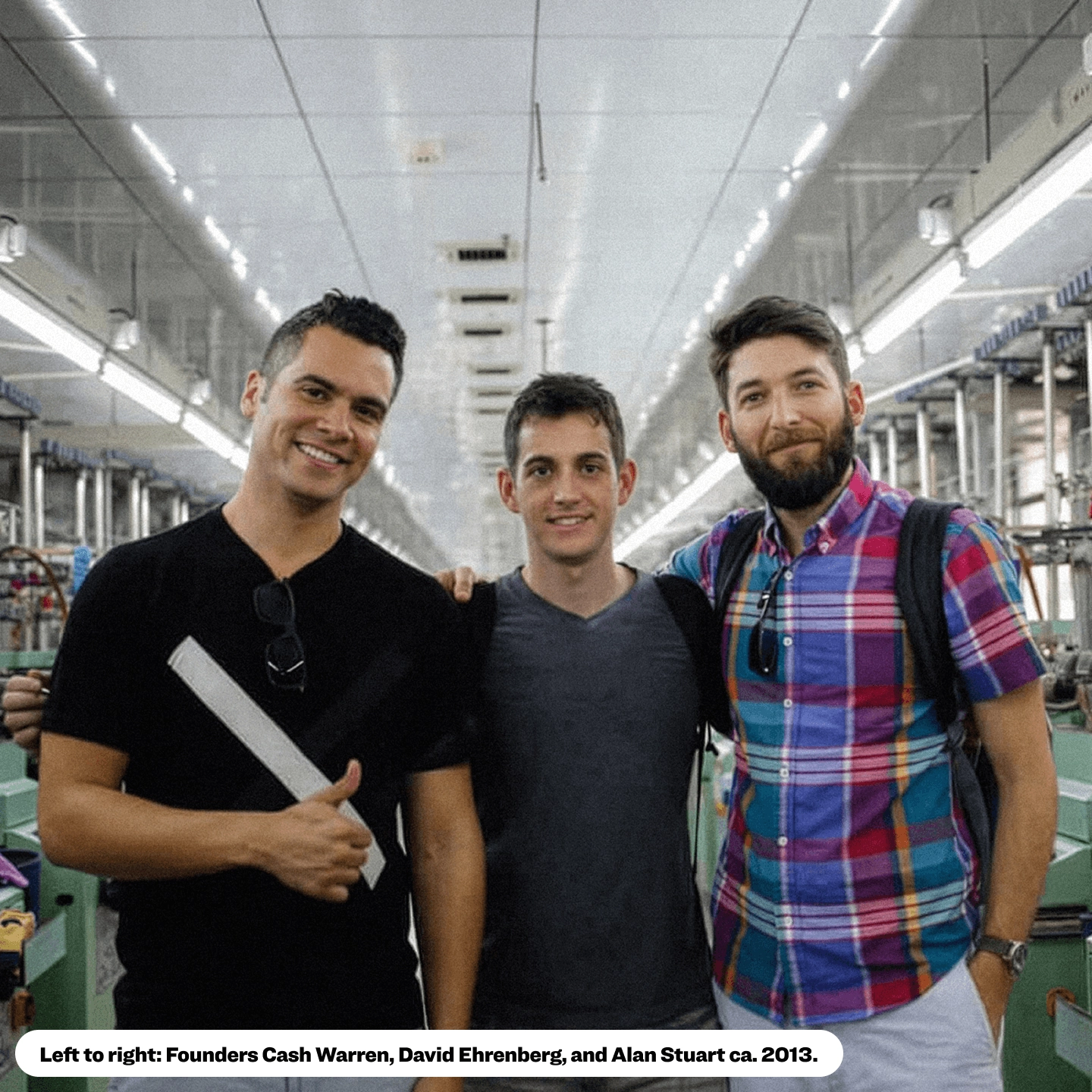 Three friends standing side by side in a factory