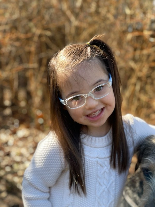 Ayala smiling outdoors in round glasses