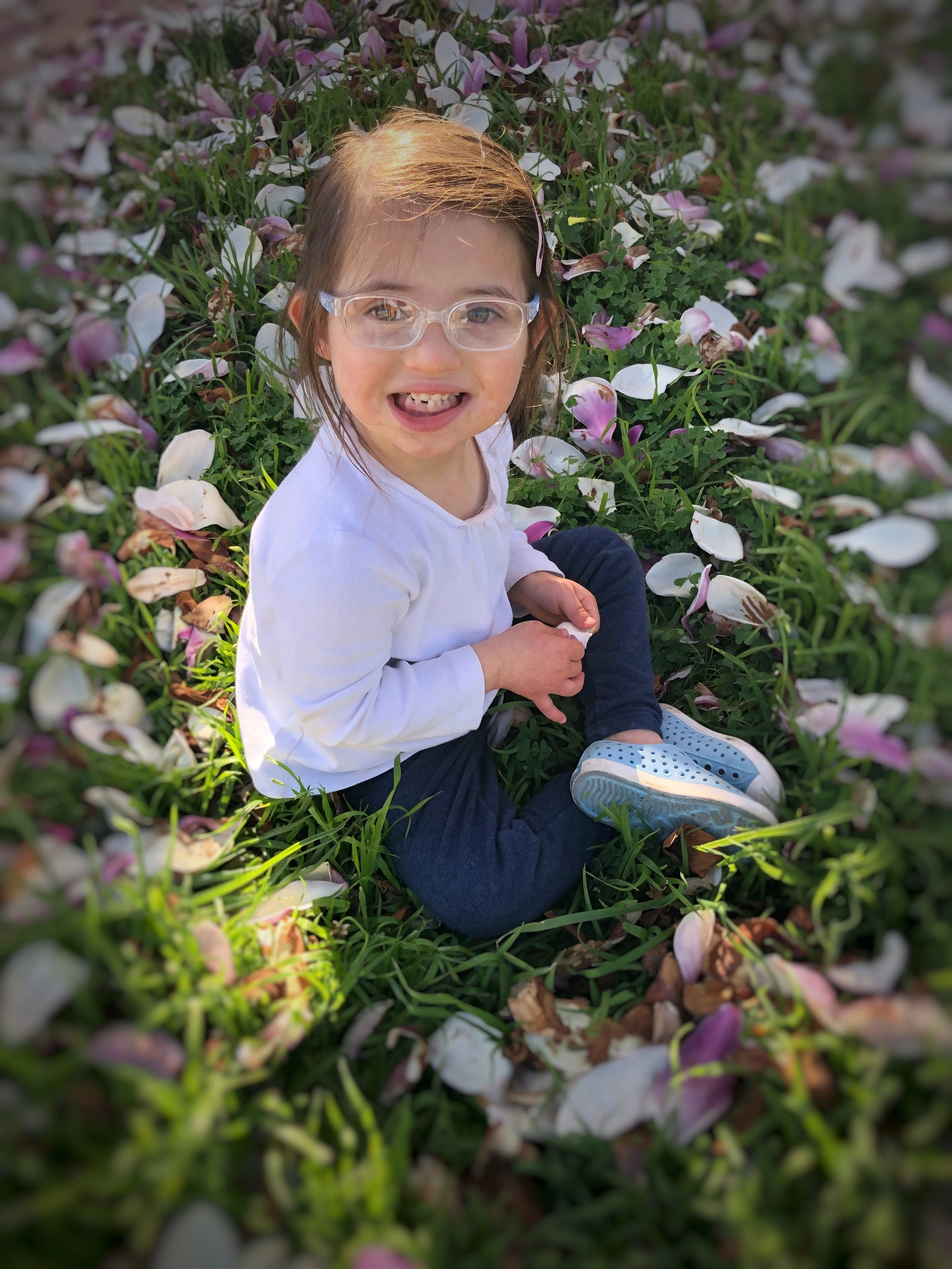 A toddler sitting among fallen blossoms